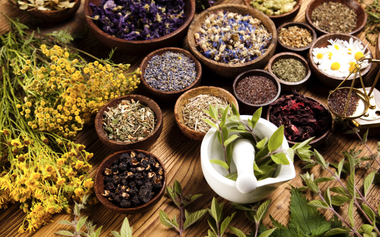 A wooden table topped with bowls of herbs and spices.