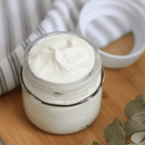 A jar of cream sitting on top of a wooden table.